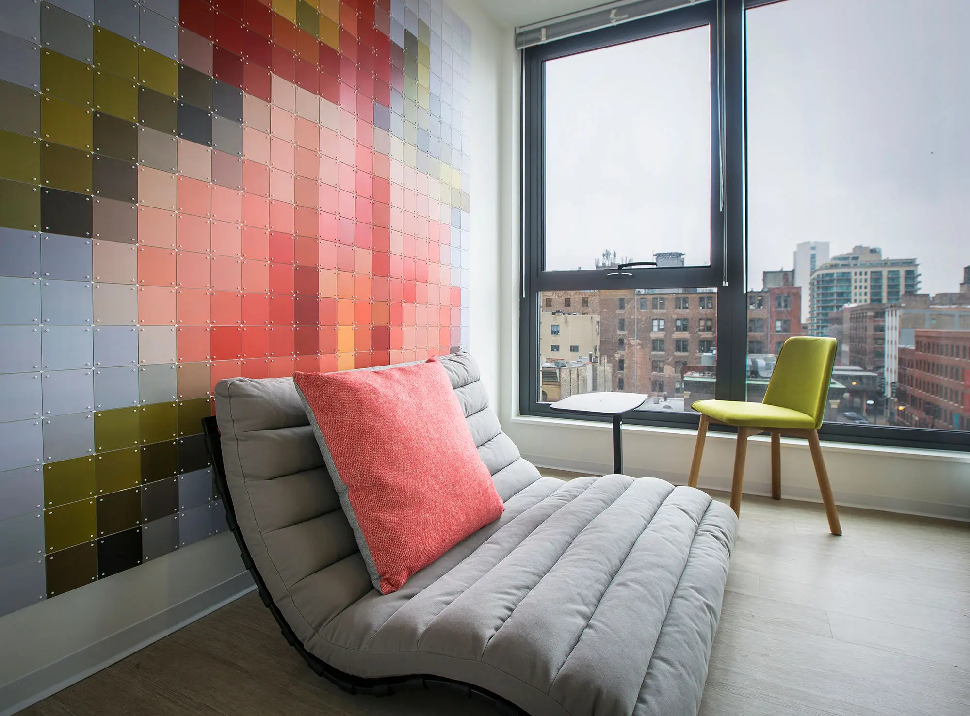 Apartment sitting nook with colorful mosaic accent wall and floor-to-ceiling Chicago skyline views at Exhibit On Superior