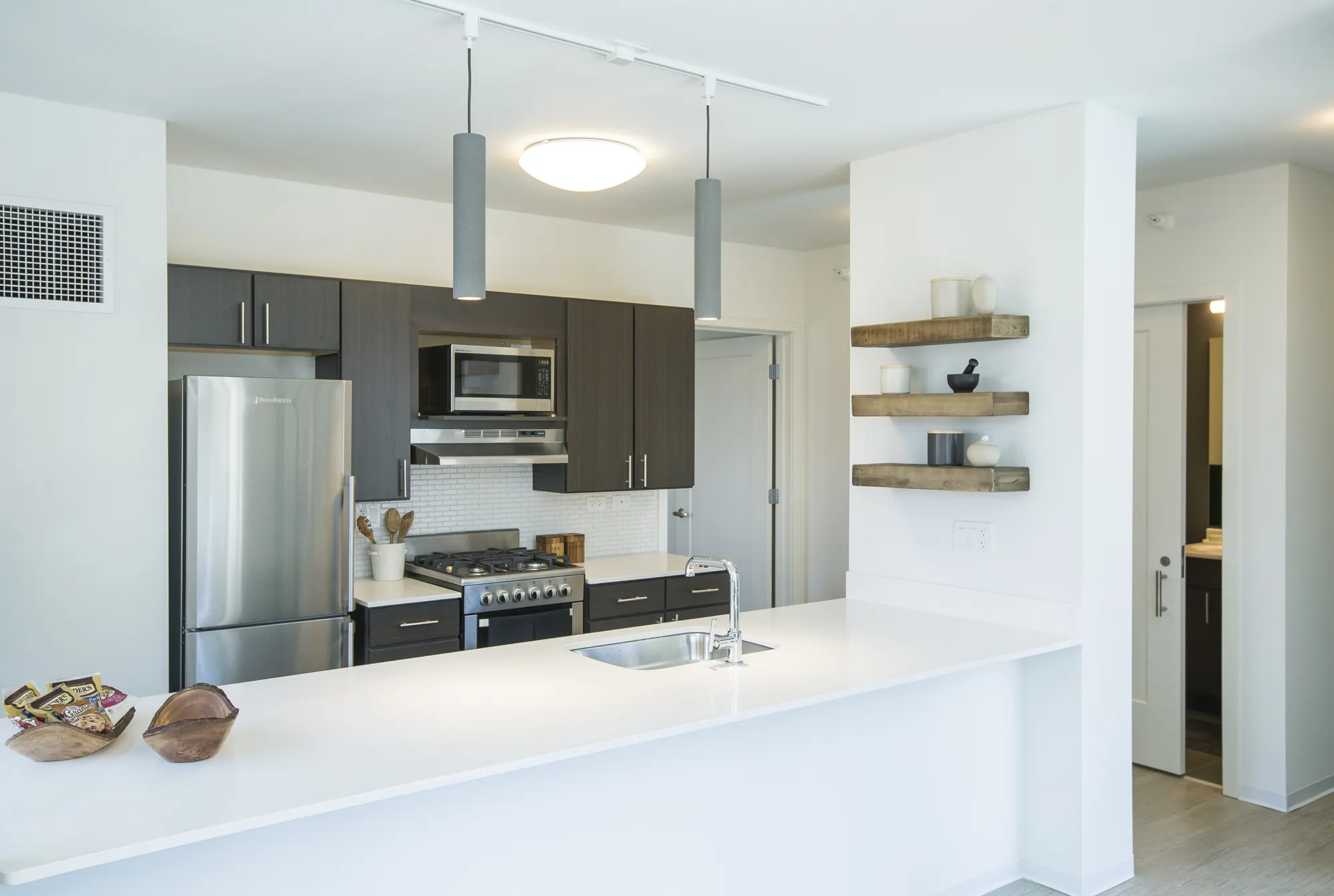Apartment kitchen with white countertops, dark cabinets, and stainless-steel appliances