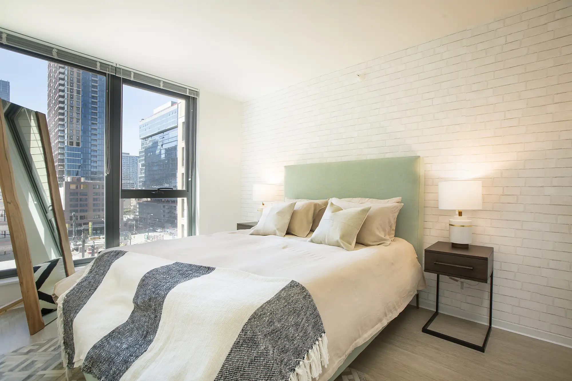 Bedroom with a neutral headboard, white bedding, and a city-facing window at Exhibit On Superior